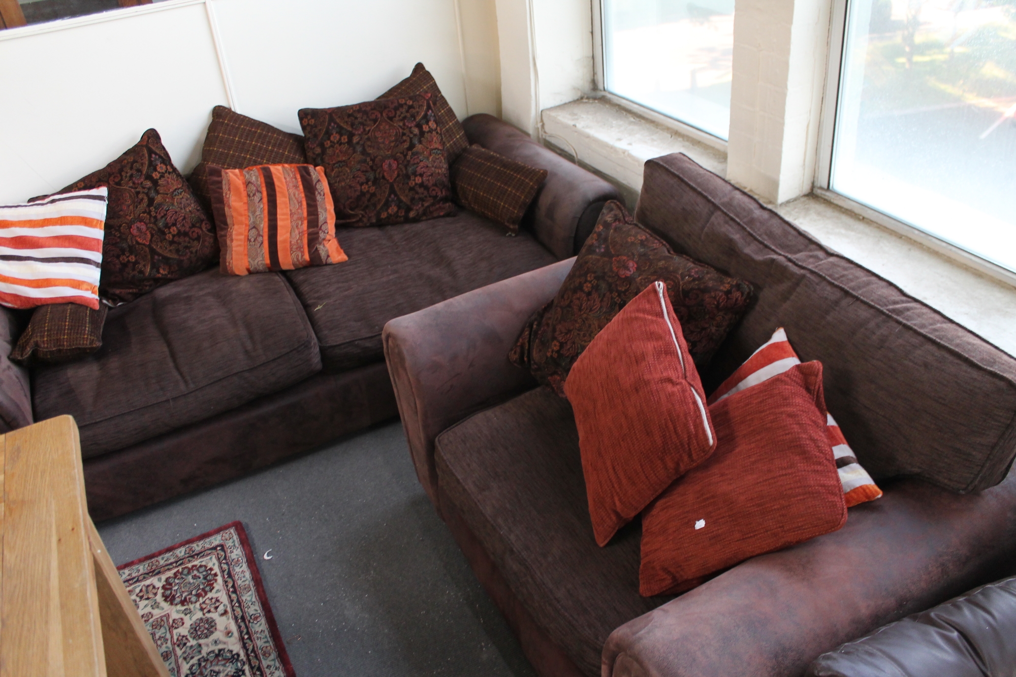 A brown suede three seater settee with scatter cushions together with the matching armchair