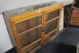 A glazed kitchen cabinet together with a further wooden bookcase