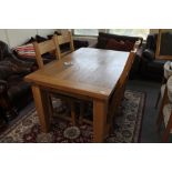 A light oak extending dining table and four ladder backed chairs