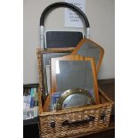 A wicker crate of teak framed mirrors, pictures and prints,