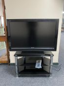 An LG 39" LCD TV with remote on black glass three tier stand