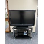An LG 39" LCD TV with remote on black glass three tier stand