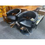 A pair of black leather swivel gas lift salon chairs on chrome bases