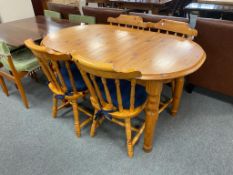 An oval pine extending table and four spindle backed chairs