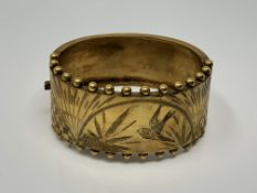 A yellow metal cuff bangle