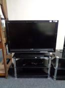 A Sony Bravia 40" LCD TV with remote on black glass three tier stand