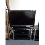 A Sony Bravia 40" LCD TV with remote on black glass three tier stand