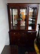 A reproduction inlaid mahogany triple door display cabinet fitted with cupboards and drawers