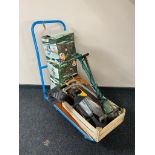 A flat bed trolley containing hand saws, electric strimmer,