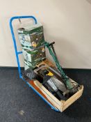 A flat bed trolley containing hand saws, electric strimmer,