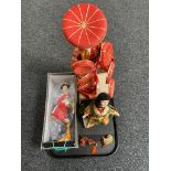 A tray of three figures of geisha on wooden stands