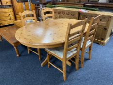 A circular pine extending table together with four ladder backed chairs