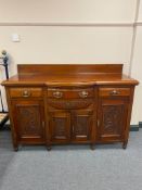 An Edwardian mahogany bow fronted sideboard fitted with three drawers and four cupboards