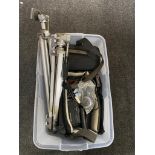 A clear plastic storage crate with lid containing camera tripods and two camcorders in carry bags