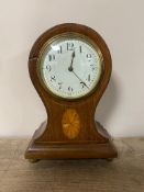 An inlaid mahogany balloon mantel clock with enamel dial on brass feet