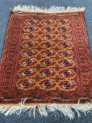 A fringed Afghan Tekke rug on orange ground