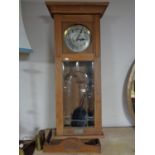 An early twentieth century oak cased wall clock with silvered dial, pendulum,