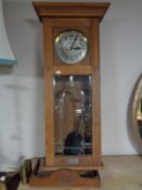 An early twentieth century oak cased wall clock with silvered dial, pendulum,