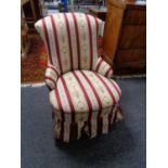 An antique nursing chair on mahogany legs in Regency striped fabric