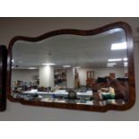 An Edwardian shaped walnut framed bevelled mirror