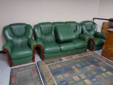 A green leather three piece lounge suite with stool