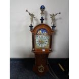 A continental oak cased wall clock with figural mounts and moonphase dial and brass weights