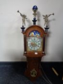 A continental oak cased wall clock with figural mounts and moonphase dial and brass weights
