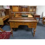 An antique pine five drawer writing desk on turned legs