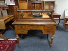 An antique pine five drawer writing desk on turned legs