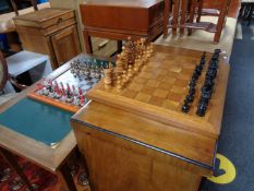 A wooden chess board with pieces together with a further chess board and pieces