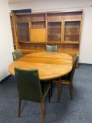 A mid century teak circular dining table with four chairs in green leather