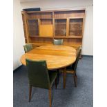 A mid century teak circular dining table with four chairs in green leather