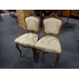 A pair of French walnut carved bedroom chairs in classical fabric