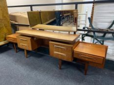 A twentieth century teak kneehole dressing table with continental headboard