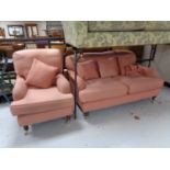 An antique style two seater settee and armchair upholstered in pink with scatter cushions