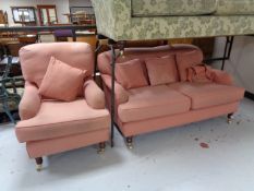 An antique style two seater settee and armchair upholstered in pink with scatter cushions