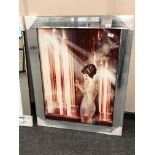 A mirrored framed picture of a lady in elegant dress