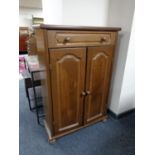 An oak double door cabinet fitted with a drawer on bun feet