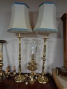 A pair of brass rise and fall table lamps with shades together with a further pair of brass lamps