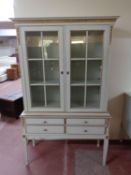 A cream and gilt double door display cabinet fitted with four drawers