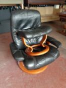 A black leather stressless swivel armchair with stool