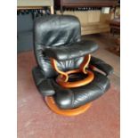 A black leather stressless swivel armchair with stool