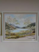 A framed oil on board - lake scene with mountains beyond by Janet Roberts