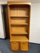 A set of teak effect open bookshelves fitted with double door cupboards below