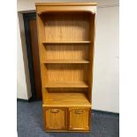 A set of teak effect open bookshelves fitted with double door cupboards below