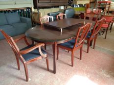 An oval mahogany effect dining table with two leaves and six shield backed chairs