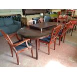 An oval mahogany effect dining table with two leaves and six shield backed chairs