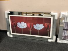 A mirrored framed picture depicting flowers