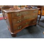 An antique mahogany serpentine fronted three drawer chest