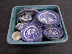 A plastic crate of blue and white willow pattern china